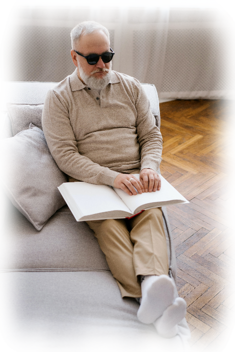 Hombre ciego sentado en el sofá leyendo Braille